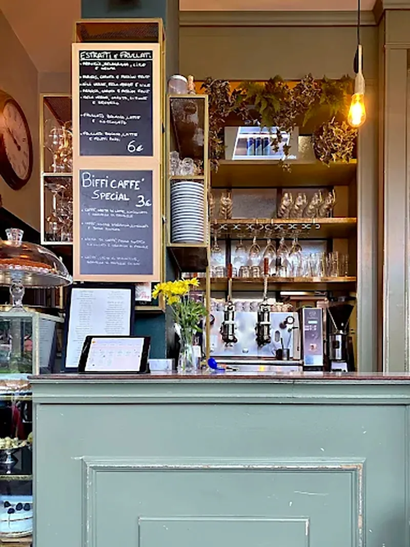 Il banco bar di Biffi: la macchina del caffè, le lavagnette con estratti e frullati e il bancone verde salvia
