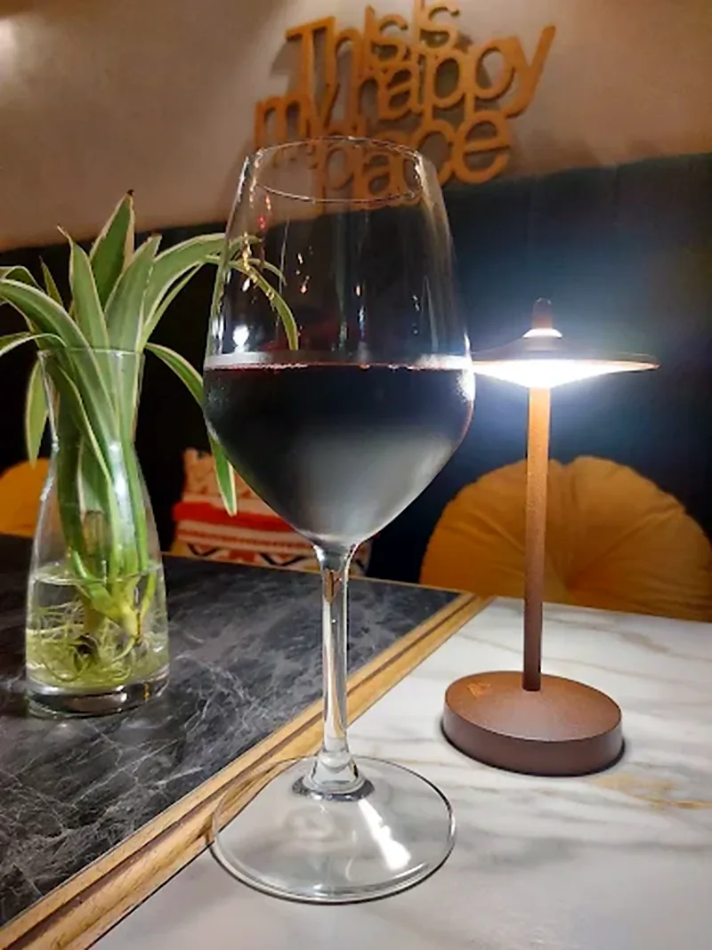 Un calice di vino rosso su un tavolo di marmo, con la scritta «This is my happy place» sullo sfondo