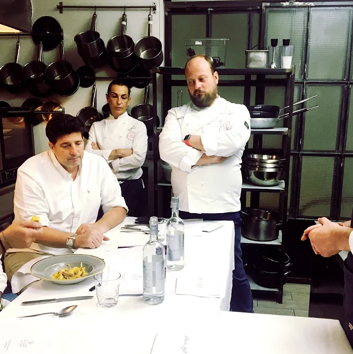 Lo staff di cucina in piedi attorno a un tavolo apparecchiato, in una cucina professionale