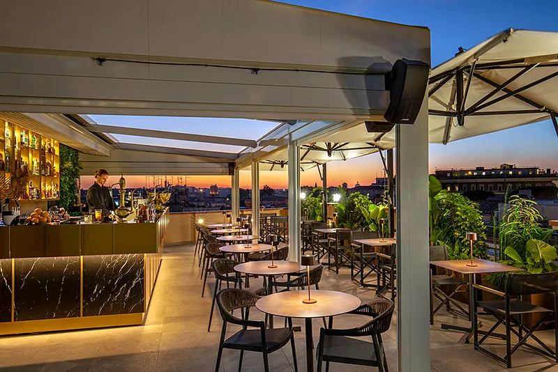 La sala all'aperto di Masa Roof Top al tramonto, con il bar illuminato e i tavoli apparecchiati