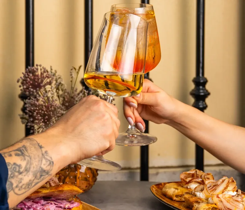 Un brindisi con due calici di vino bianco, con taglieri e focacce sul tavolo