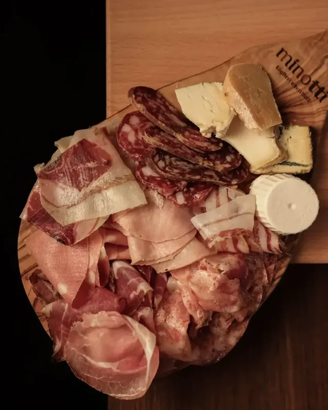 Tagliere di salumi e formaggi su un piano di legno con il marchio Minotti