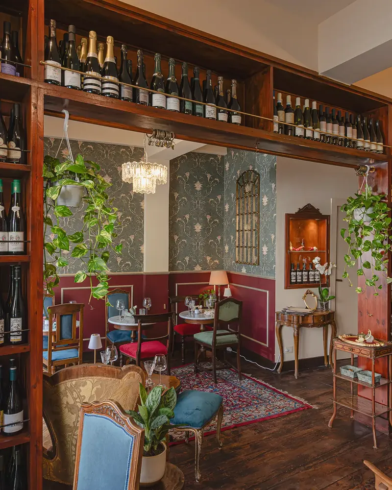 La sala di Notramè: carta da parati, poltroncine e la libreria dei vini